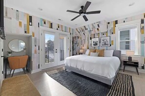 Ein modernes Schlafzimmer mit Bett, Deckenventilator, Schreibtisch, Stuhl und großem Fenster.