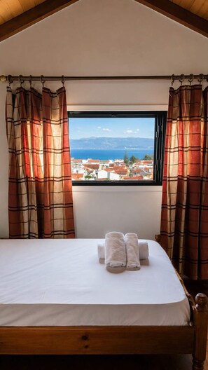 Un dormitorio con cama, dos toallas y una ventana con cortinas.