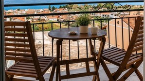 A balcony with two wooden chairs and a small round table, overlooking a coastal town and mountains. - Gavriil Apartments Corfu - Seaview Studio Retreat (Kavos)
