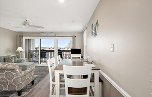 A dining area with a table and chairs, a ceiling fan, a view through a glass door, and a sign above the door. - Updated 2 BR 2 BA Unit - 1/2 Block from the Beach (Ocean City)