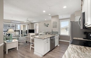 A modern kitchen with white cabinetry, a granite countertop, and a built-in dishwasher. - Updated 2 BR 2 BA Unit - 1/2 Block from the Beach (Ocean City)