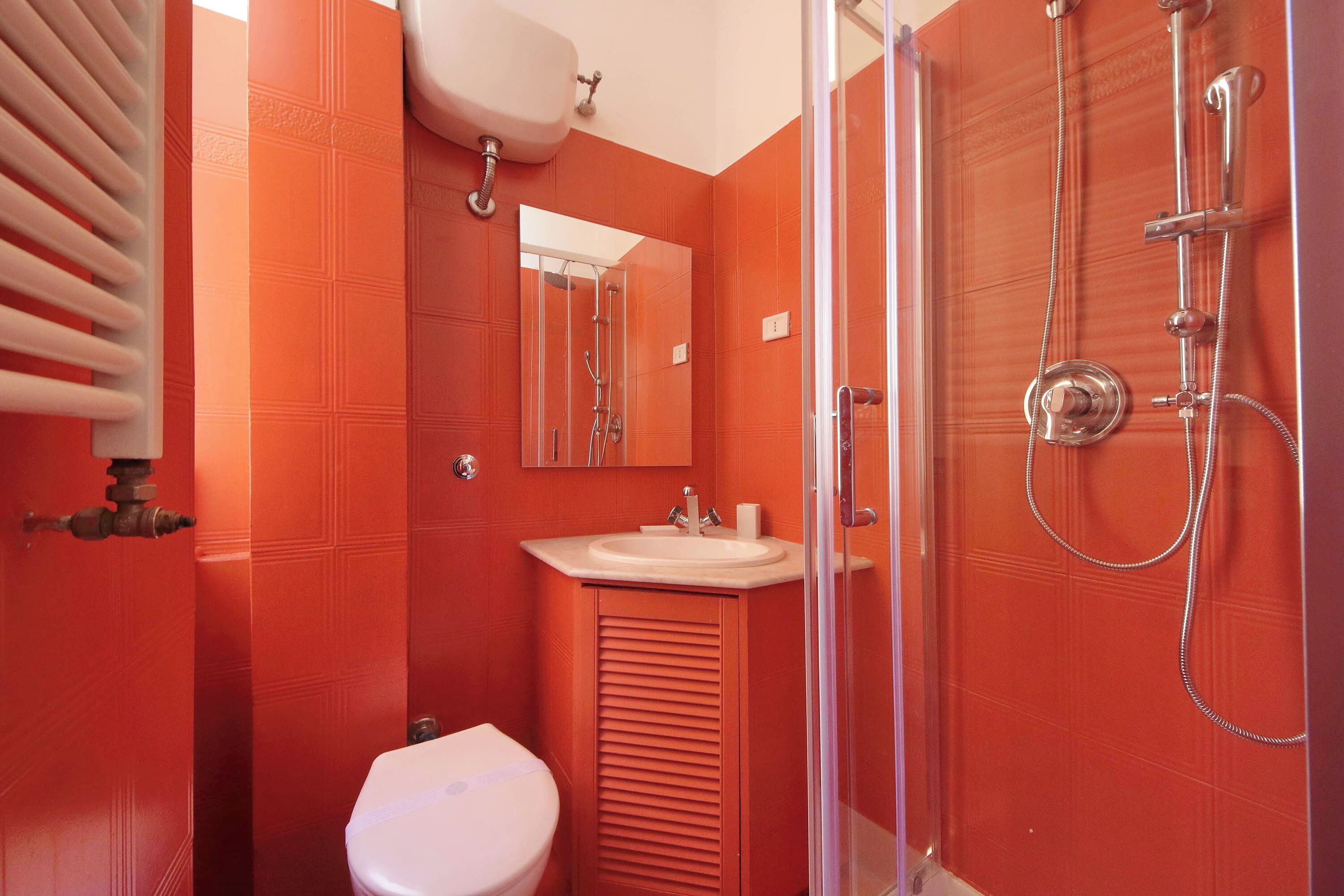 Ein Badezimmer mit Toilette, Waschbecken, Spiegel und Dusche.