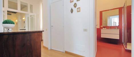 A room with a wooden desk, a white door, and a red-framed mirror.