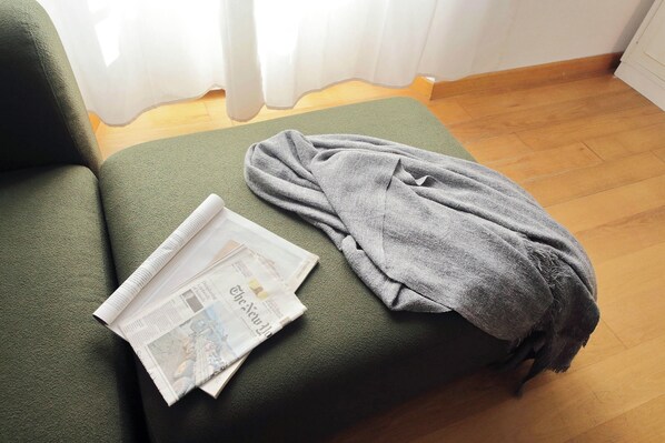 A green sofa with a newspaper and a grey blanket. - Italianway Collection - Casa Tibullo (Rome)