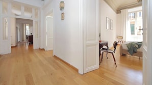 Een ruime kamer met houten vloeren, witte muren en een eethoek met een tafel en stoelen.