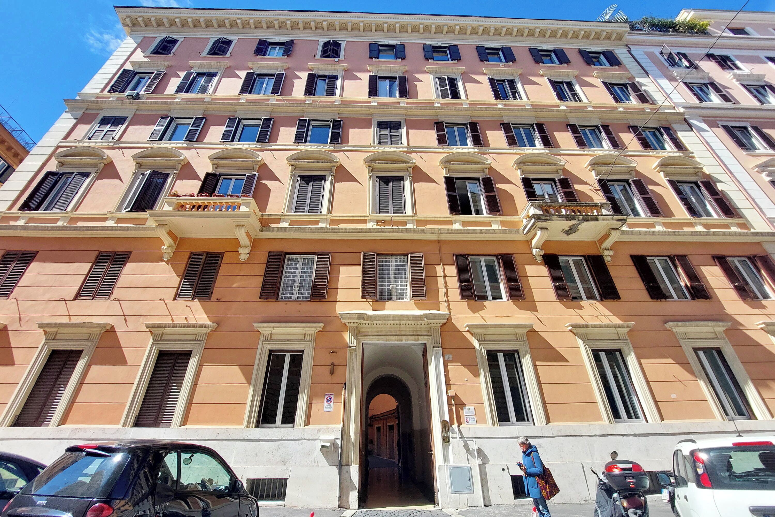 Un edificio de varios pisos con entrada central, balcones y cielo despejado.
