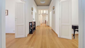 Een gang met witte deuren, een houten vloer en een boekenplank.