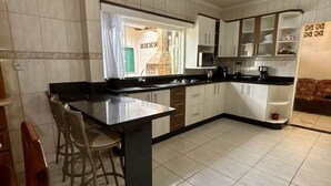 Una cocina moderna con una isla central, taburetes de bar y vista al área de comedor.