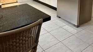 Una cocina moderna con un refrigerador de acero inoxidable, un microondas y un comedor con una mesa y sillas de mimbre.