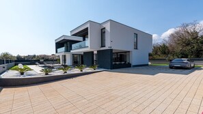 A modern two-story house with a flat roof, large windows, and a paved driveway. - Luxury Villa Asper with Pool and Jacuzzi (Ližnjan)