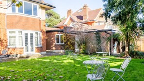 A residential property with a well-maintained lawn, patio furniture, and a brick house with multiple windows.