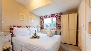 A bedroom with a bed, a bedside table, a nightstand, a wardrobe, a window with curtains, and a radiator.