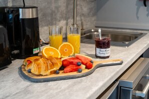 A breakfast setup with croissants, strawberries, blueberries, oranges, and a jam jar on a wooden board. - Cransley Room 4 - Ground floor room close to the beaches and town (Bournemouth)