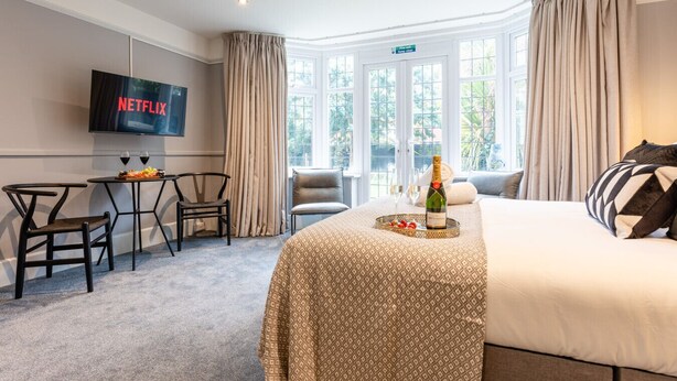 Una camera d'hotel con un letto, una TV che mostra Netflix, una bottiglia di champagne e un vassoio per la colazione.