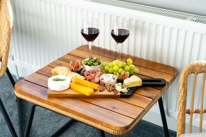 A wooden table with a cheese board, grapes, figs, and two glasses of red wine. - Cransley Room 6 - Close to beaches and town with shared garden (Bournemouth)