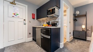 Eine kompakte Küche mit Kühlschrank, Mikrowelle und einbauendem Backofen.
