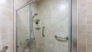 Eine Duschkabine mit Handbrause, einer Haltestange und Ablage für Toilettenartikel.