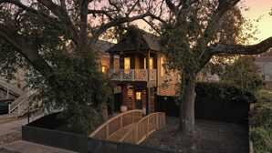 Ein zweistöckiges Holzhaus mit Balkon, umgeben von Bäumen.