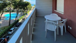Ein Balkon mit Tisch und Stühlen mit Blick auf einen Swimmingpool und einen strahlend blauen Himmel.