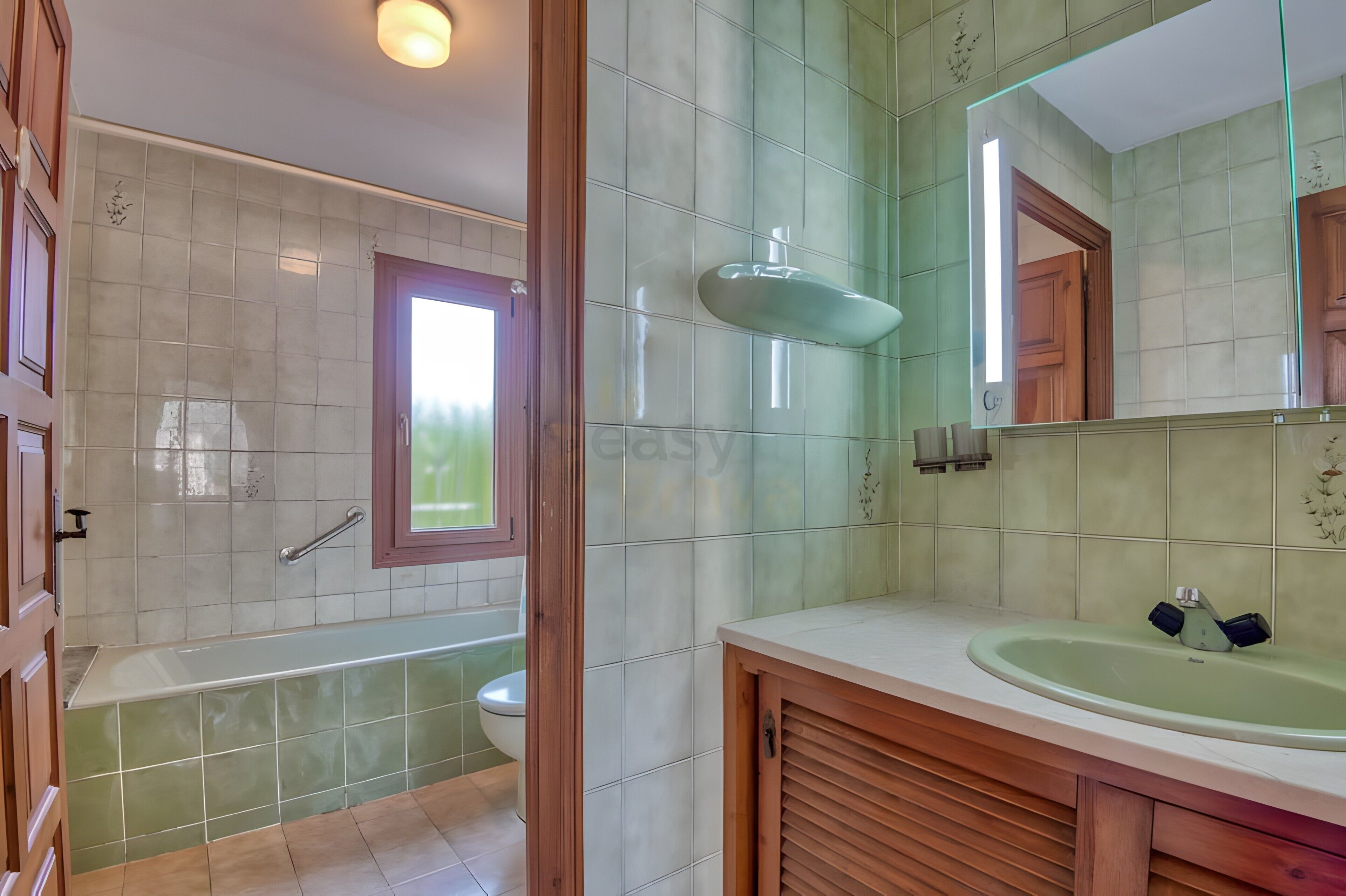 A bathroom with a bathtub, toilet, sink, and a large mirror.