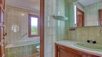 A bathroom with a bathtub, toilet, sink, and a large mirror.