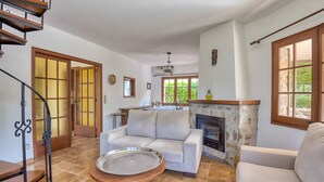 Ein Wohnzimmer mit Sofa, Kamin, Essbereich und Treppe.