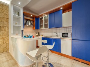 A modern kitchen with blue cabinets, a white island, and a stainless steel sink.