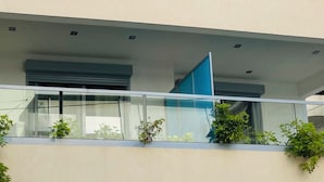 Edifício com vários andares, design arquitetônico moderno, com varandas de vidro e telhado plano.