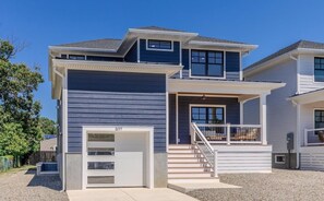 A two-story house with a garage, a staircase, and a balcony. - Slacktide Bay Retreat - Walk to Beach - Hot Tub, Fire Pit, Gazebo - Sleeps 10 (Lower Township)