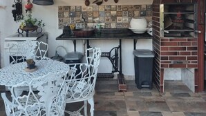 A kitchen with a brick oven, hanging utensils, and a tiled backsplash.