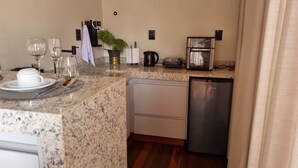 A kitchen with granite countertops, a coffee maker, a kettle, a toaster, and a dishwasher.