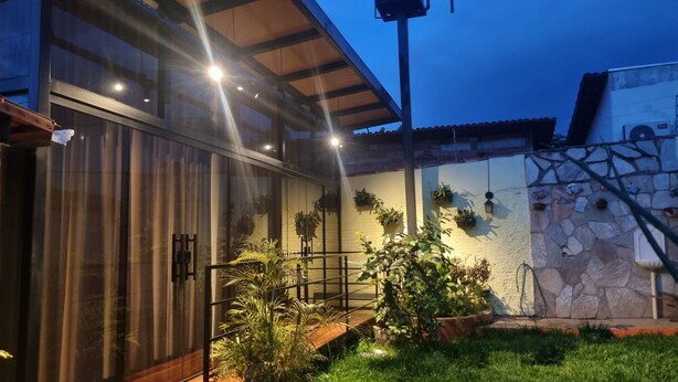 A modern house with a large glass door, a wooden deck, and potted plants.