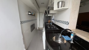 A modern kitchen with a stainless steel sink, black countertop, and tiled backsplash. - Charming 2-bedroom Apartment With Ocean View in Rio (Rio de Janeiro)
