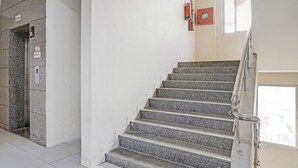 A staircase with granite steps, a handrail, and a fire extinguisher mounted on the wall. - THE BULL GROUP INTERNATIONAL (Surat)
