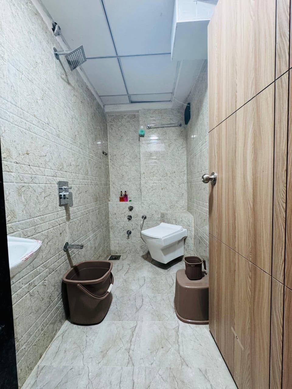 A bathroom with a marble floor, a sink, a shower, and a wooden cabinet.