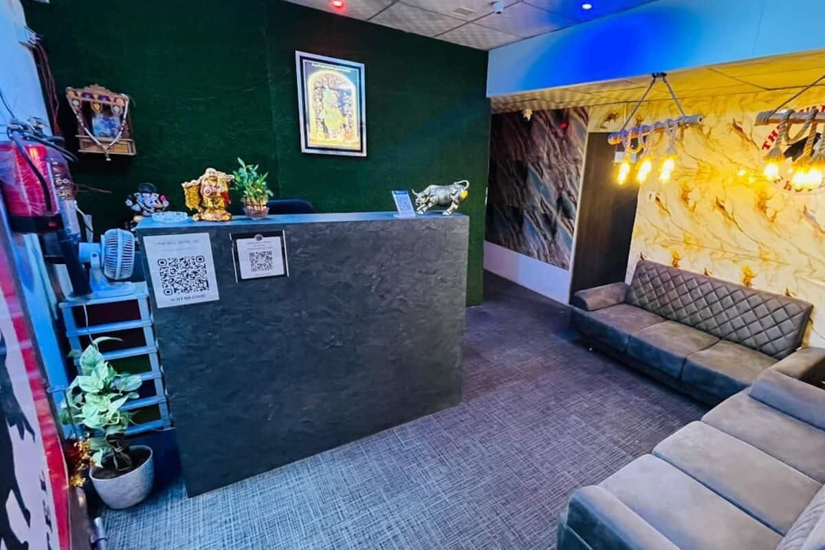 Un área de recepción con un mostrador oscuro, un espacio de descanso con asientos acolchados y una pared con una lámpara decorativa.