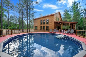 Eine Holzhütte mit Pool, umgeben von Bäumen.