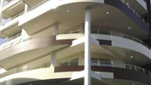 A multi-story building with a curved facade, balconies on each floor, and a central vertical structure. - Luxury Accommodation With Panoramic Terrace (Lignano Sabbiadoro)