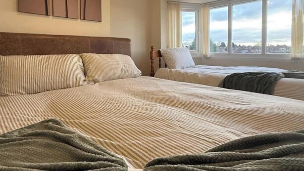 Camera d'albergo con due letti, un'ampia finestra vista città, un lampadario decorativo e tre opere d'arte a parete.