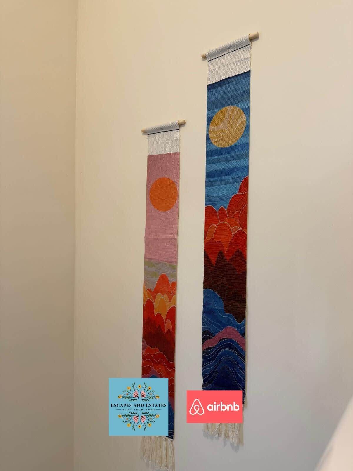 Two vertical tapestries with abstract designs on a wall.