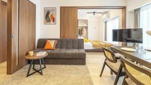 Une chambre d’hôtel moderne équipée d’un canapé, d’une table à manger, d’un téléviseur et d’une armoire.