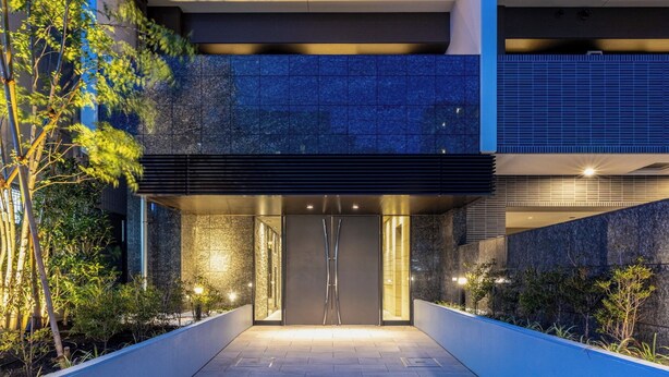 Un bâtiment moderne doté d’une entrée en verre, d’un chemin et d’un espace verdoyant environnant.