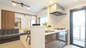 Une cuisine moderne dotée d’une cuisinière intégrée, d’un coin repas avec un canapé et une chaise, et d’une grande fenêtre qui laisse entrer la lumière naturelle.