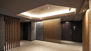 Un intérieur moderne avec un plafond encastré, des lambris en bois, des murs en pierre et un sol carrelé.