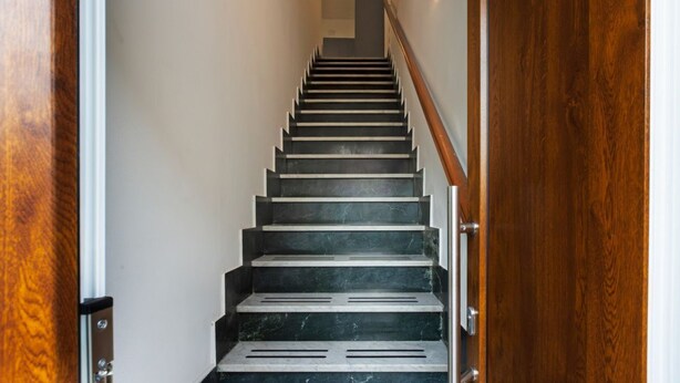 A staircase with a wooden handrail and a door at the bottom. - A cozy and spacious 80 square meters apartment, perfect for four people, located on the first floor of a typical Sant'Antioco building (NO elevator).The property is located a short distance from the town center and offers quick access to the seafront. It (Sant'Antioco)