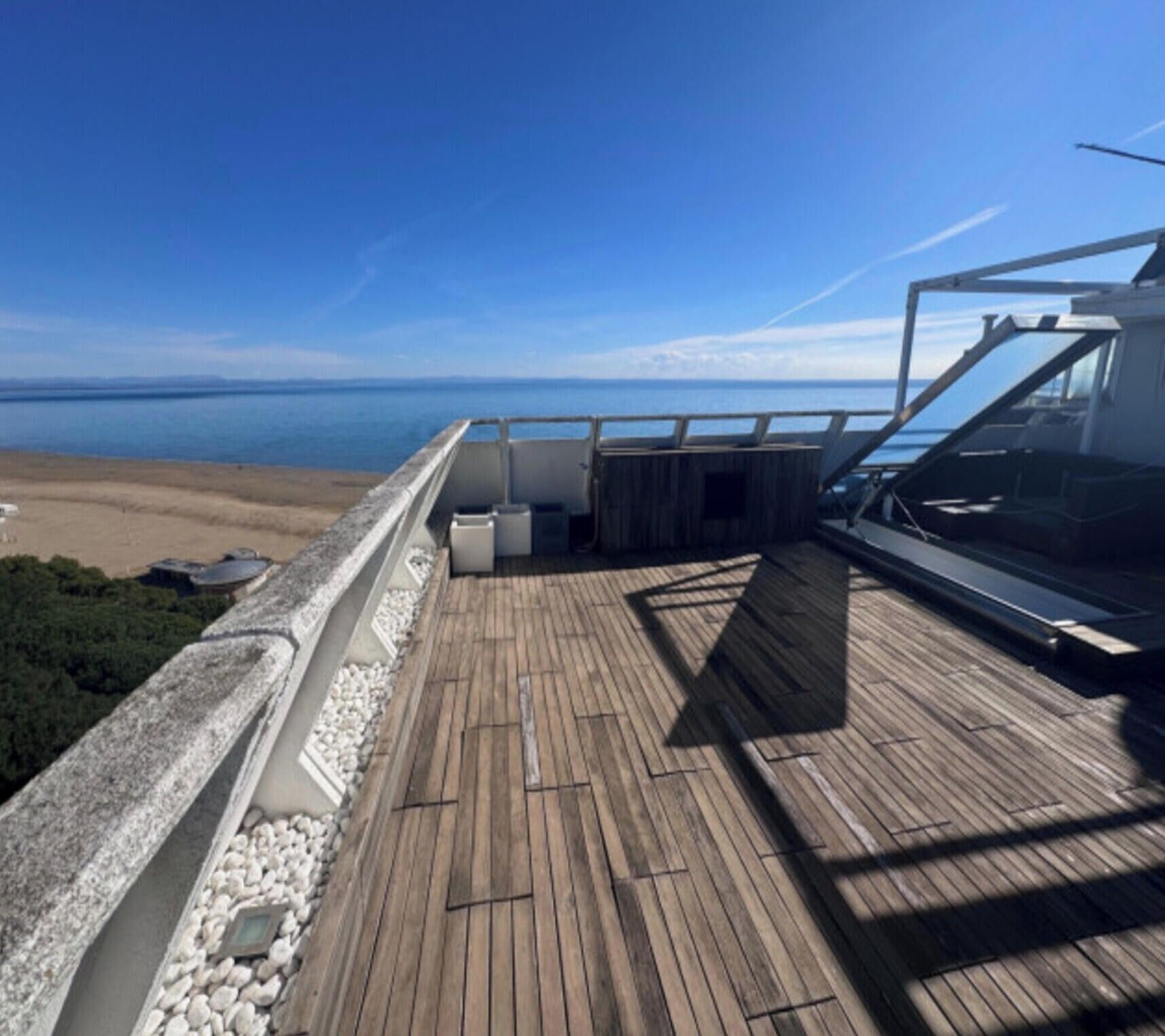 Una terraza de madera con vista al océano, una barandilla y un banco.