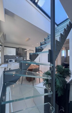 Ein modernes Interieur mit Wendeltreppe aus Glas, einer Küchenzeile und einem Essbereich.