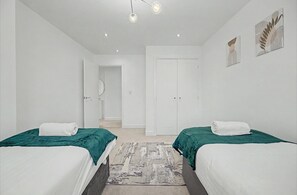 A hotel room with two beds, a hallway, and a door leading to a bathroom. - 4-bed House, Sleeps 9 w/ Garden and Parking (Newport)
