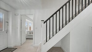 A staircase with a black railing, a white door, and a carpeted floor.