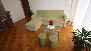 A living room with a sofa, ottomans, a glass coffee table, and a potted plant. - Apartment for 4 with sea view, balcony and parking in Jadranovo (Jadranovo)